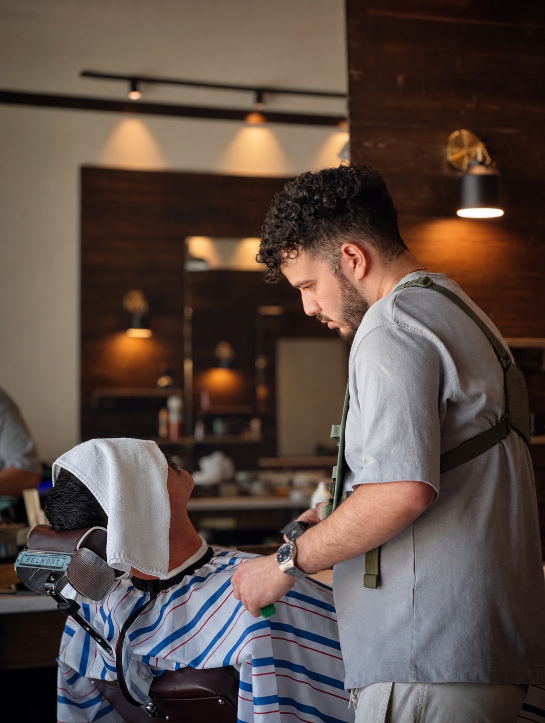 A Minty barber preparing a client for a beard service with a warm towel